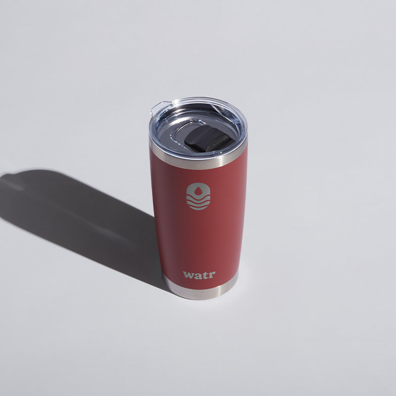 Alt text: "Red 20 oz WATR branded tumbler with a clear sliding lid, prominently featuring the company&