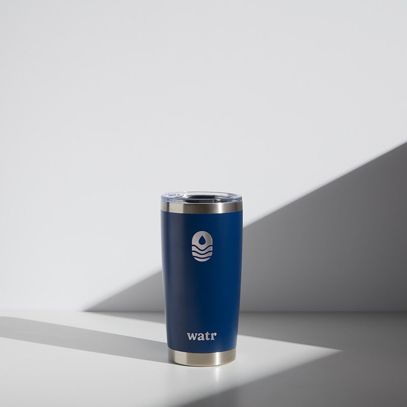 Alt text: "20 oz WATR branded tumbler in blue featuring the company logo, displayed on a light gray background with a subtle shadow."