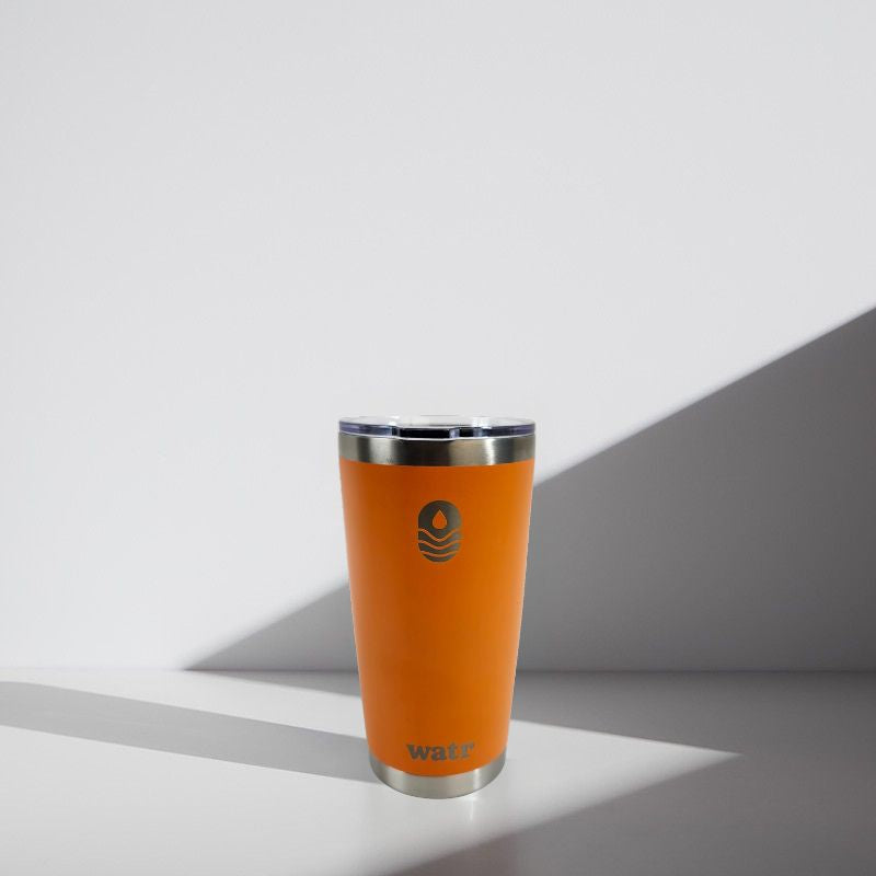 Orange tumbler with a silver rim on a light gray background