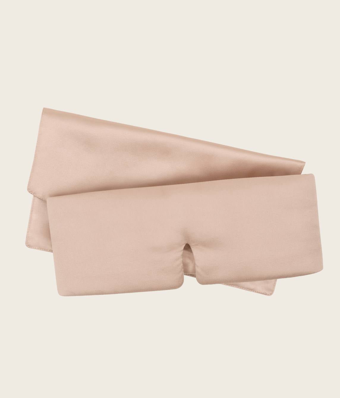 A silk sleep mask flatlay on a white background with the silky pouch behind it [44377020825819, 47185819467995]
