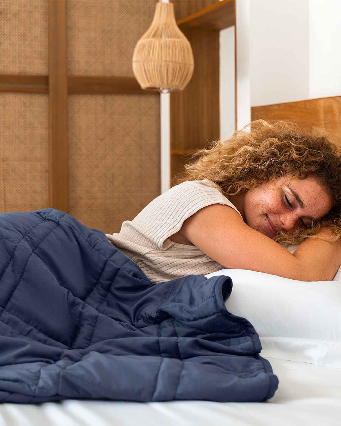 A young woman with red curly hair lies in a bed with a blue weighted blanket across her body. [43649942782171, 45574417875163, 44422804340955, 45574418137307, 44422811287771, 46452818510043, 44422816432347, 46452819067099, 47185819762907, 47185819992283, 47185820025051, 47185820123355, 46301293543643, 46301293773019, 46301293805787, 46301293904091]