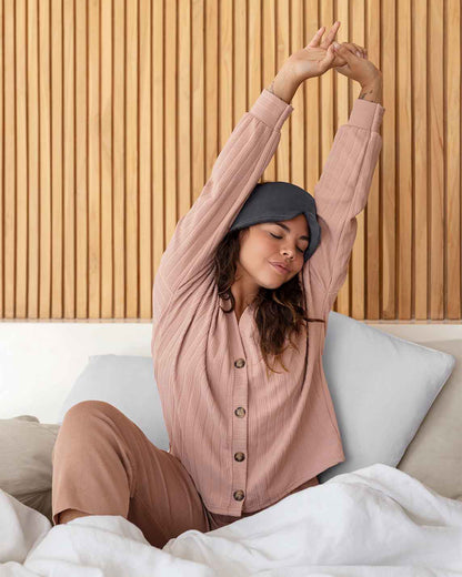 A young woman reaches up stretching wearing a silk sleep mask on her head [44377020793051, 47185819435227]