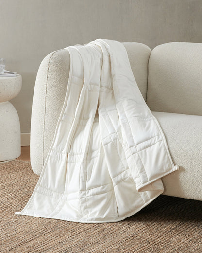 pebble white weighted blanket draped over the arm of an ivory sofa [42934587621595]