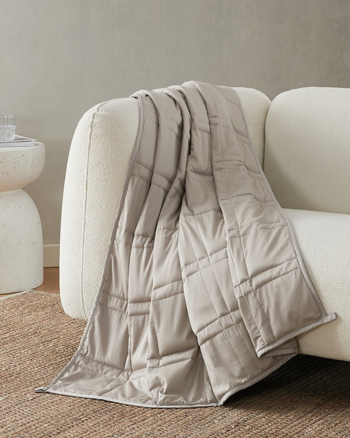 pebble white weighted blanket draped over the arm of an ivory sofa [42952280801499]